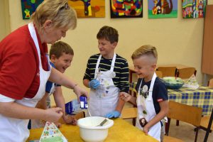 Frau Bornemann von ALEXMENÜ schmeckt mit den Grundschulkindern den Fruchtjoghurt ab