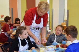 Frau Bornemann erklärt den Kindern, wie die Äpfel geschnitten werden müssen