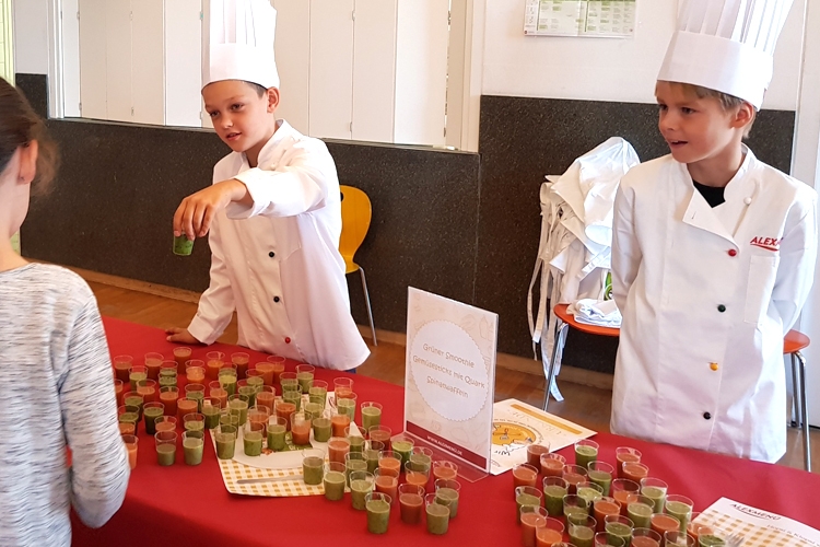Es gibt zwei verschiedene Sorten Smoothies zu verkosten. Ausgewählte Kinder präsentieren ihren Mitschülern, was sie in dem Projekt zubereitet haben. ©ALEXMENÜ