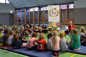 Diätassistenin und Projektleiterin Marina Bornemann erklärt den Kindern den Bewegungspass, den sie zum absolvieren des gesamten Parcours erhalten.