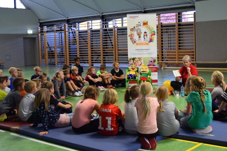 Diätassistenin und Projektleiterin Marina Bornemann erklärt den Kindern den Bewegungspass, den sie zum absolvieren des gesamten Parcours erhalten.