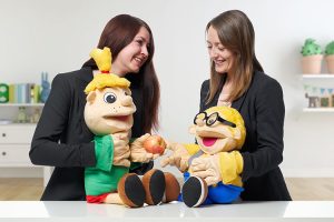 Warum gesunde Ernährung wichtig ist? Das erklären Diätassistentin Juliane Kumstel und Ernährungswissenschaftlerin Lydia Röder (v.l.) Kindern mit Hilfe der ALEXMENÜ-Maskottchen Hopsi und Klopsi.