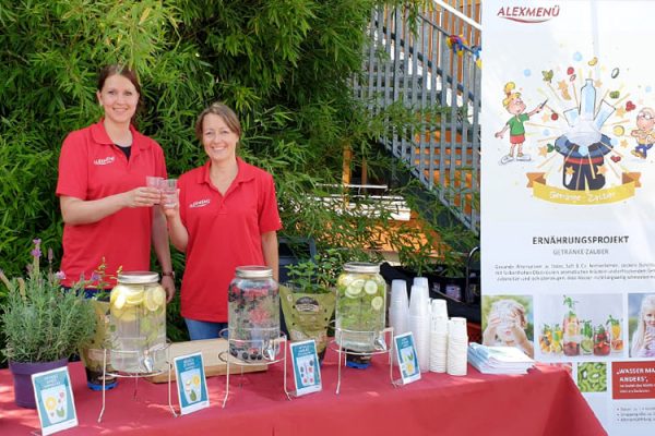 Diätassistenin Juliane Kumstel und Ernährungswissenschaftlerin Lydia Röder (v.l.) schenken aromatisiertes Wasser auf dem Schulfest aus.