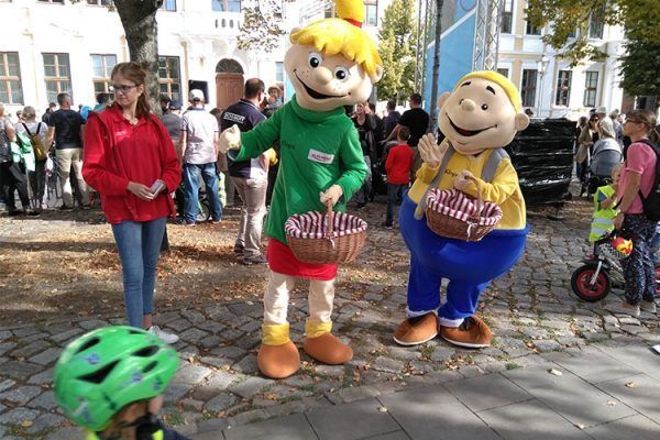 Die Maskottchen Hopsi und Klopsi feuern die Kinder beim Laufradrennen an und verteilen frische Äpfel.