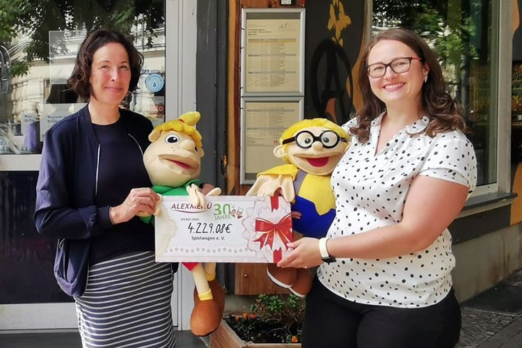 Antonia Hillmann (ALEXMENÜ) (v.r.) überreicht Liane Kanter (Spielwagen e.V.) einen Scheck in Höhe von über 4000 Euro.